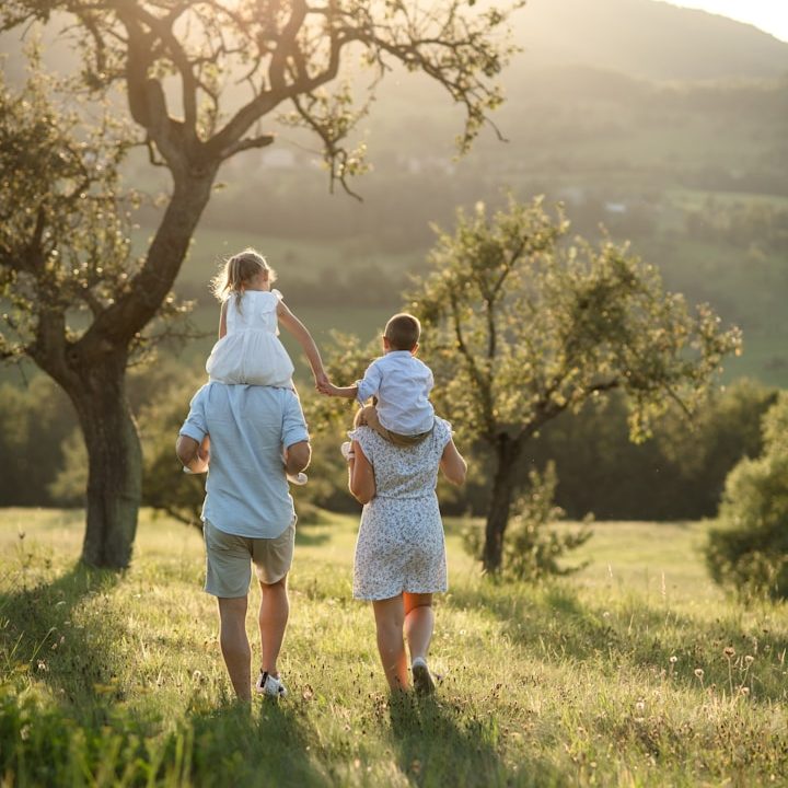 Eine Familie mit zwei Kindern, die in einem Landschaftsgebiet spazieren geht.