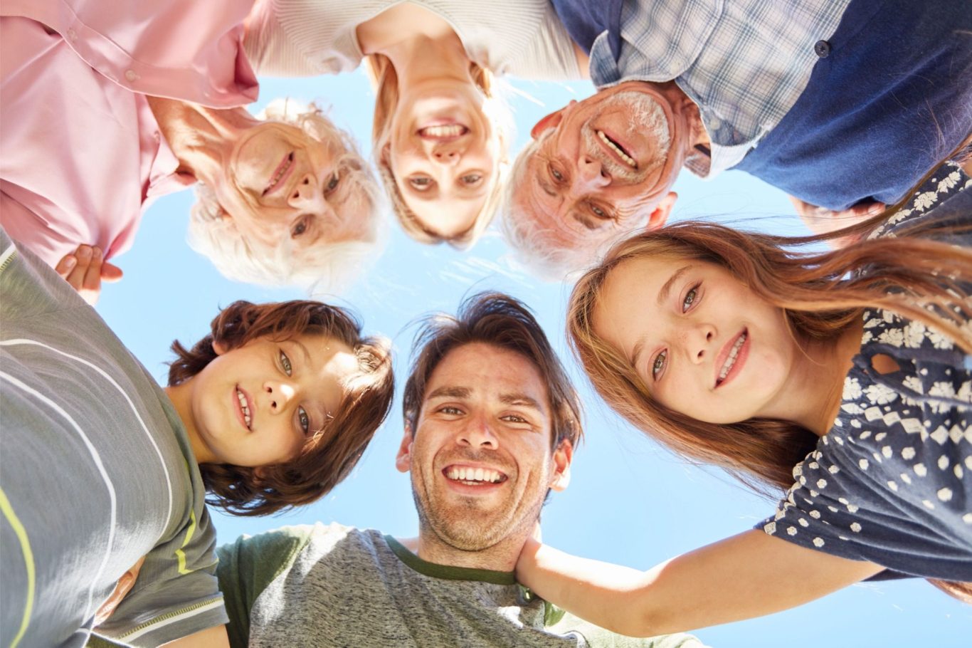 Eine fröhliche Gruppe von sechs Personen lächelt nach unten in die Kamera.