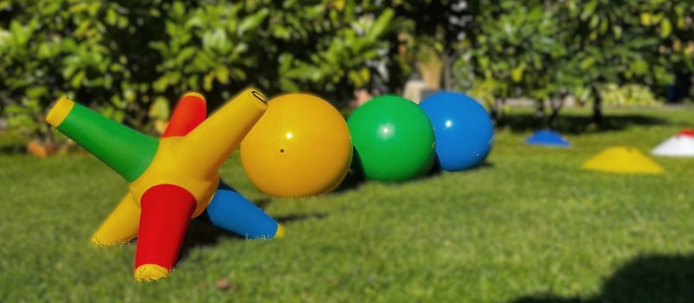 Bunte Spielzeugformen und Bälle in einem Garten auf grünem Gras.