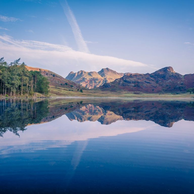 Berglandschaft mit glattem See, das jenseits der Wasseroberfläche gespiegelt wird.